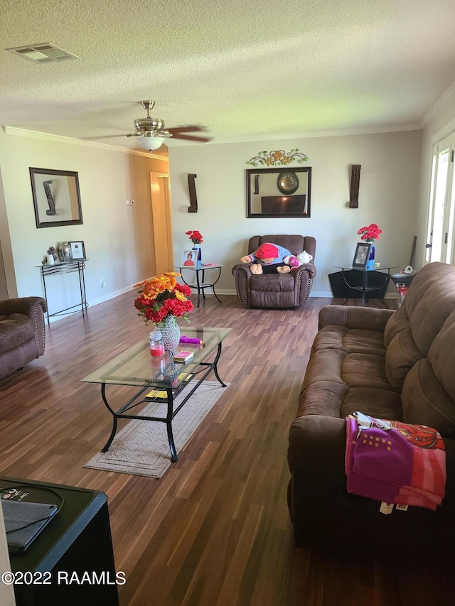 living room with ceiling fan, hardwood / wood-style flooring, ornamental molding, and a textured ceiling