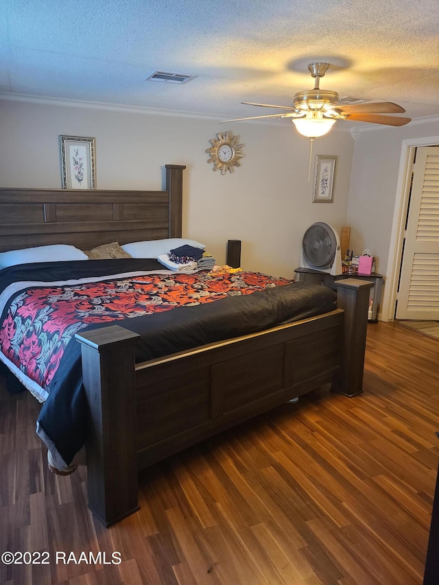 bedroom featuring ceiling fan, hardwood / wood-style flooring, ornamental molding, and a textured ceiling