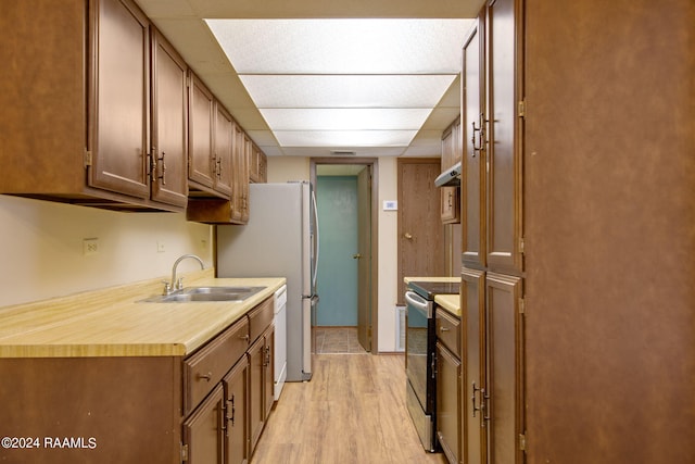 kitchen featuring wall chimney range hood, light hardwood / wood-style flooring, stainless steel range with electric cooktop, white dishwasher, and sink