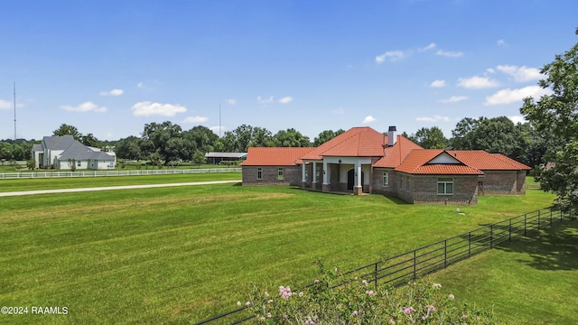 exterior space featuring a lawn, a tile roof, a chimney, a rural view, and fence