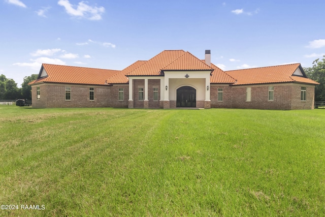 view of front of house with a front lawn, a chimney, a tile roof, and brick siding