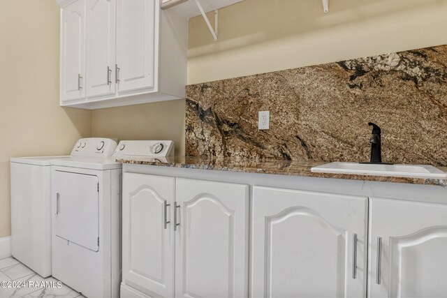 clothes washing area with sink, washer and dryer, cabinets, and light tile patterned floors