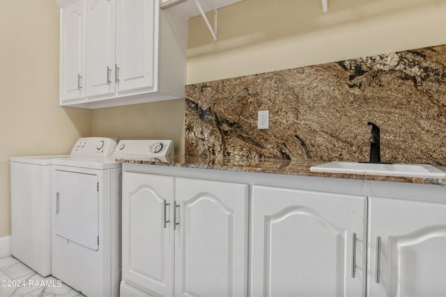 clothes washing area with washing machine and dryer, cabinet space, and a sink