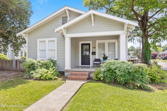 bungalow-style home featuring a front yard and covered porch