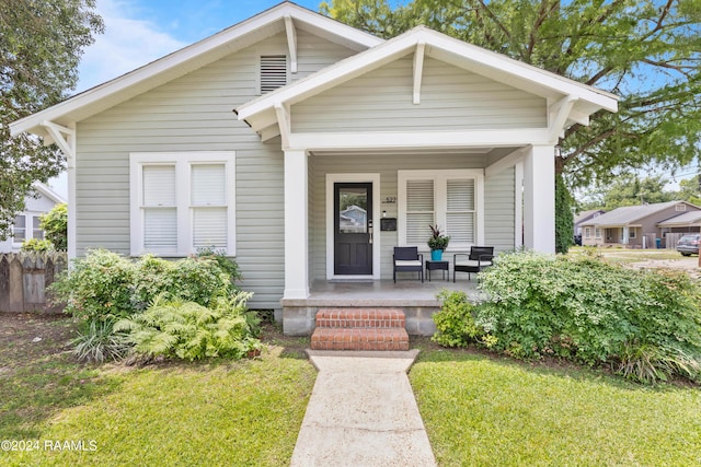 bungalow featuring covered porch and a front lawn