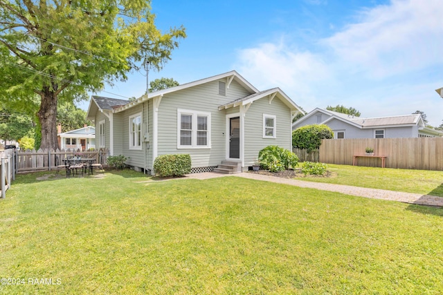 view of front of home with entry steps, a fenced backyard, and a front lawn