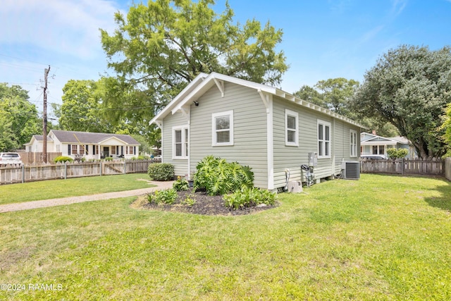 view of side of home with central air condition unit, fence private yard, and a lawn