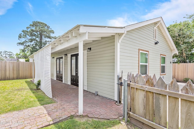 view of side of home with a yard, a fenced backyard, and a patio