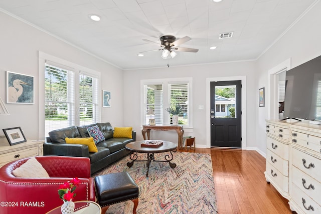 living room with light wood-style floors, visible vents, and crown molding