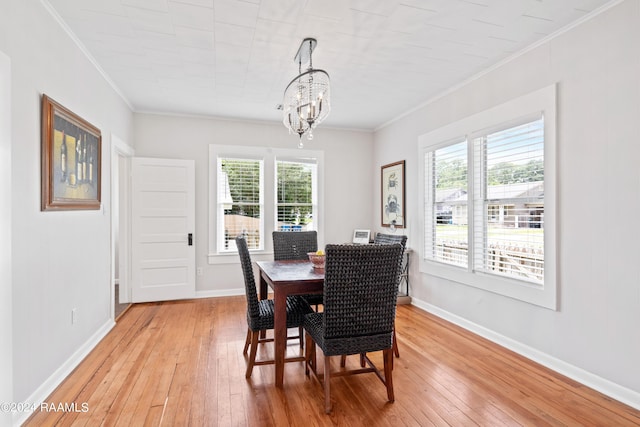 dining space with ornamental molding, light wood-style floors, and baseboards