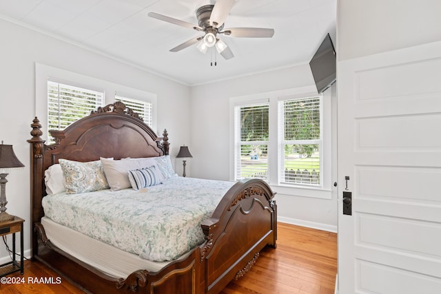 bedroom featuring ornamental molding, multiple windows, and light wood-style flooring