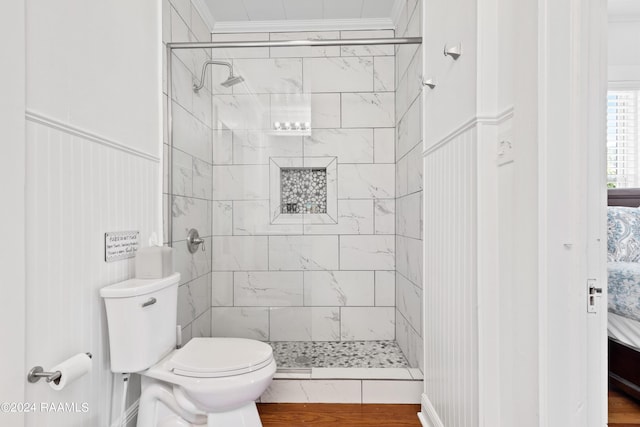 bathroom with toilet, a shower stall, ornamental molding, and wainscoting