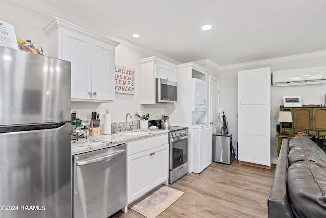 kitchen featuring open floor plan, a wall mounted air conditioner, stainless steel appliances, stacked washing maching and dryer, and a sink