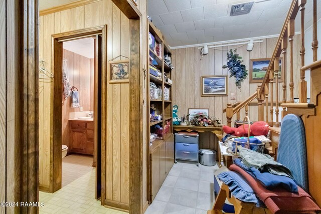 935 Pearl St, Rayne, LA 70578 - miscellaneous room featuring light floors, visible vents, a sink, wood walls, and stairs