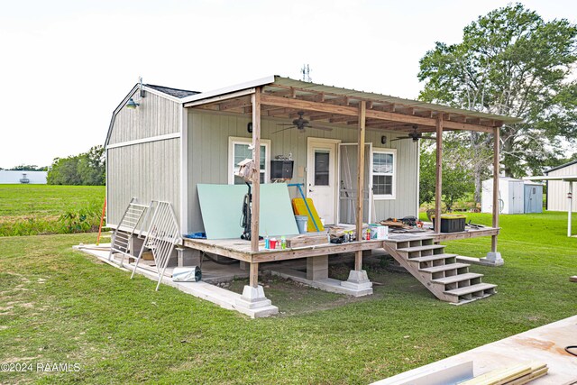 rear view of property featuring a yard, a shed, and ceiling fan