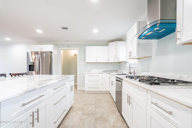 kitchen with appliances with stainless steel finishes, white cabinets, sink, and wall chimney range hood