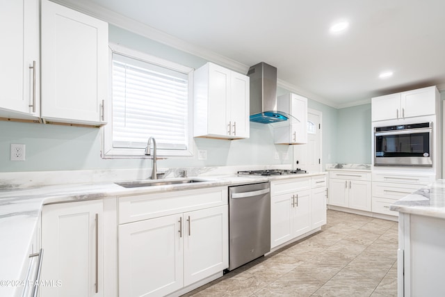 kitchen with ornamental molding, appliances with stainless steel finishes, wall chimney range hood, and white cabinetry