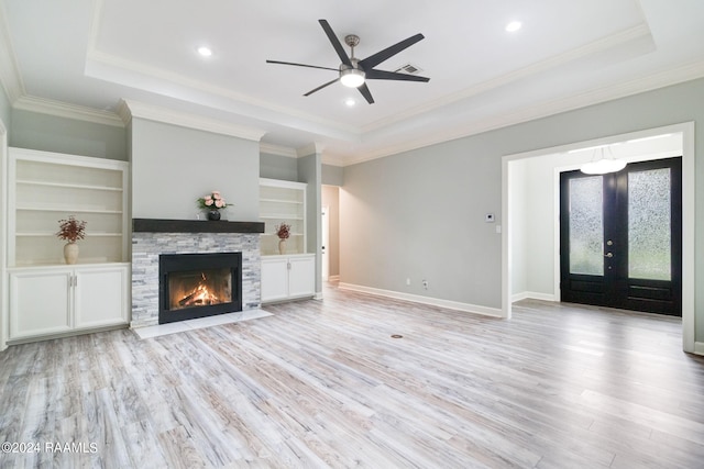 unfurnished living room with a raised ceiling, light hardwood / wood-style floors, and crown molding