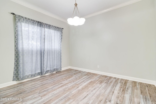 spare room featuring crown molding, hardwood / wood-style floors, and a chandelier