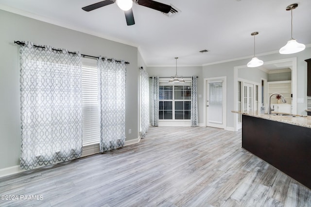 unfurnished living room with sink, ornamental molding, light hardwood / wood-style flooring, and ceiling fan