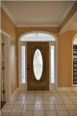 foyer with crown molding and light tile patterned floors