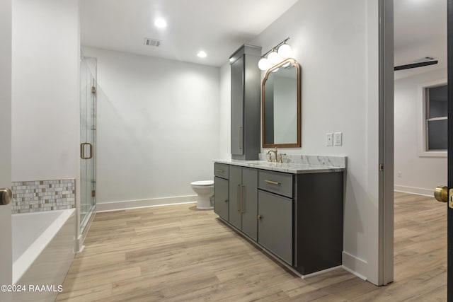 full bathroom featuring hardwood / wood-style floors, independent shower and bath, vanity, and toilet