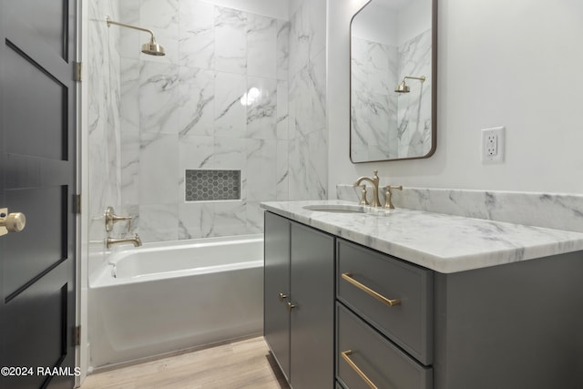 bathroom featuring wood-type flooring, vanity, and tiled shower / bath combo