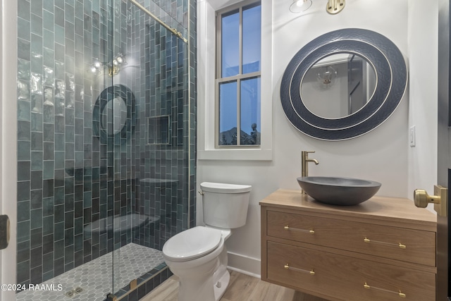 bathroom featuring vanity, hardwood / wood-style floors, toilet, and a shower with shower door