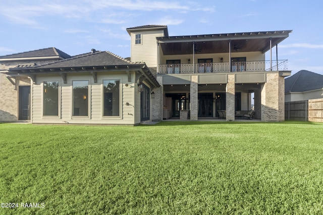 rear view of property with a balcony and a yard