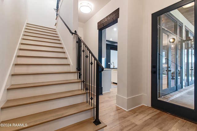 foyer entrance with light hardwood / wood-style floors, sink, french doors, and a barn door