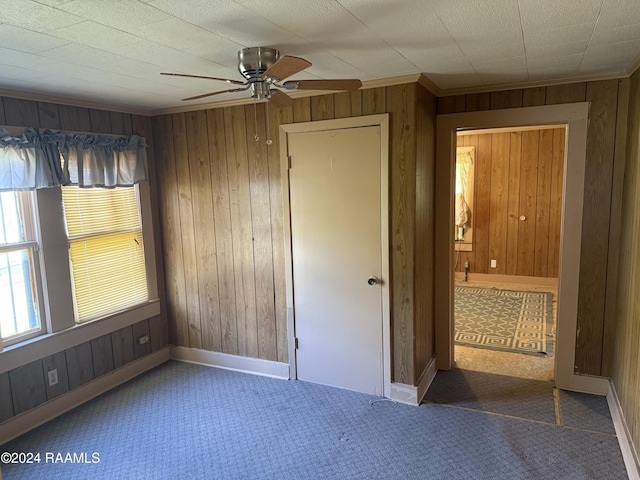 unfurnished bedroom with wooden walls, dark carpet, and ceiling fan