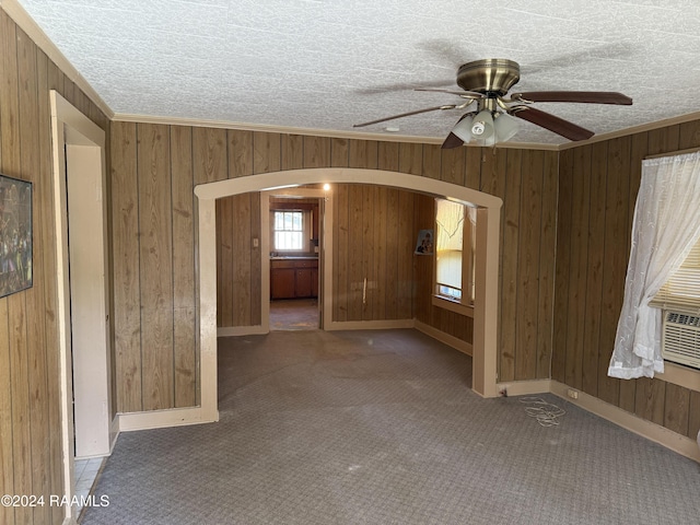 1010 W Simcoe St, Lafayette, LA 70501 - carpeted spare room with arched walkways, wood walls, a ceiling fan, and a textured ceiling