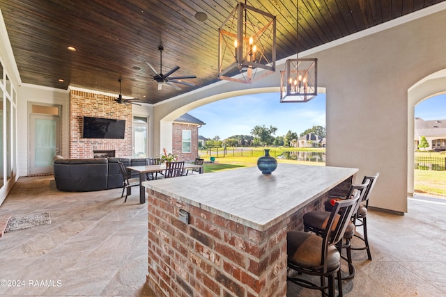 view of patio with an outdoor brick fireplace, ceiling fan, and an outdoor bar