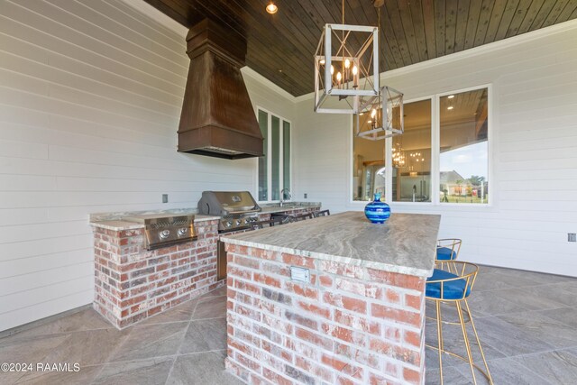 kitchen featuring wood walls, decorative light fixtures, premium range hood, wood ceiling, and crown molding