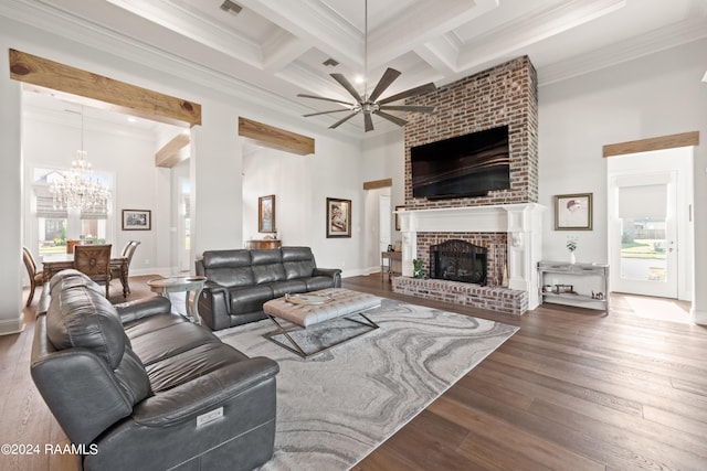 living room with hardwood / wood-style floors, ceiling fan with notable chandelier, crown molding, and a brick fireplace