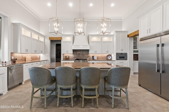 kitchen featuring a kitchen island, custom range hood, backsplash, appliances with stainless steel finishes, and white cabinetry