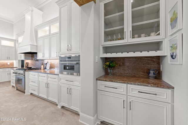 kitchen featuring white cabinets, stone counters, appliances with stainless steel finishes, custom exhaust hood, and decorative backsplash