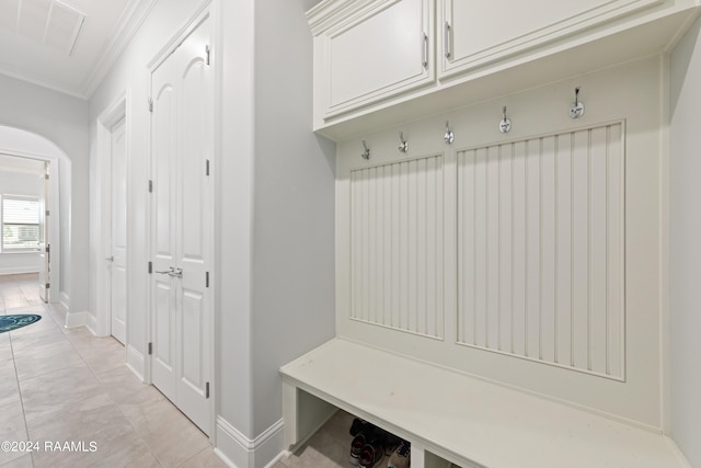 mudroom with light tile patterned floors and crown molding