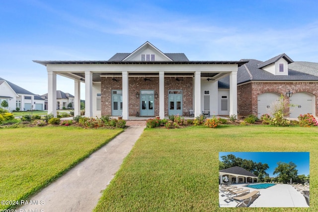 view of front of home with a garage, covered porch, and a front lawn