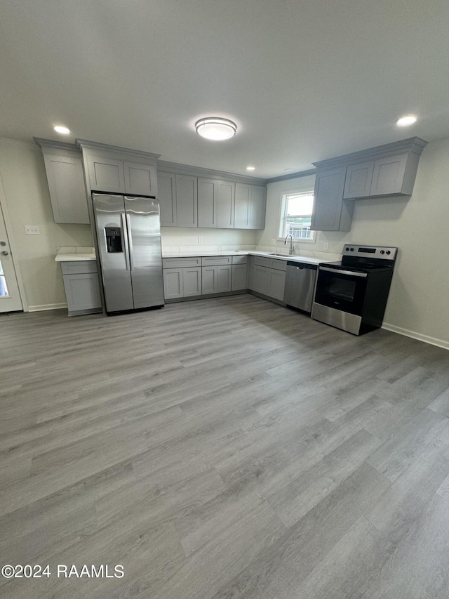 kitchen featuring appliances with stainless steel finishes, sink, gray cabinetry, and light wood-type flooring