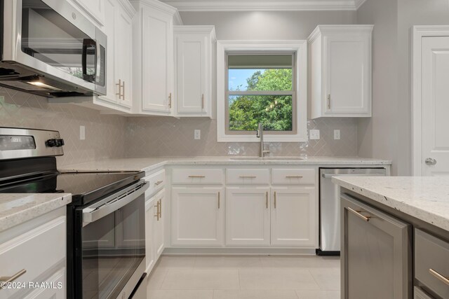 kitchen featuring tasteful backsplash, white cabinets, light stone counters, and stainless steel appliances