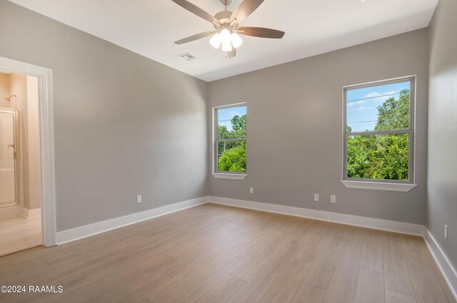 spare room with ceiling fan, light wood-type flooring, and plenty of natural light