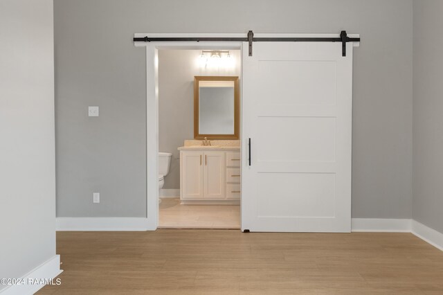 interior space with ensuite bath, light hardwood / wood-style flooring, a barn door, and sink