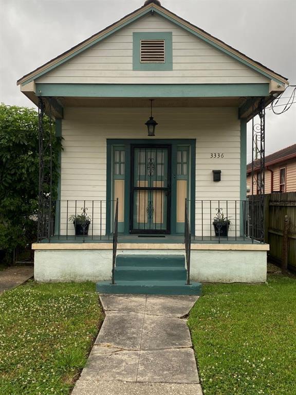 doorway to property featuring a yard, french doors, covered porch, and fence