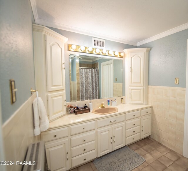 bathroom with crown molding, tile walls, tile patterned flooring, and vanity