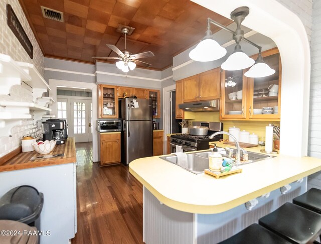 kitchen with appliances with stainless steel finishes, ornamental molding, dark hardwood / wood-style floors, kitchen peninsula, and ceiling fan