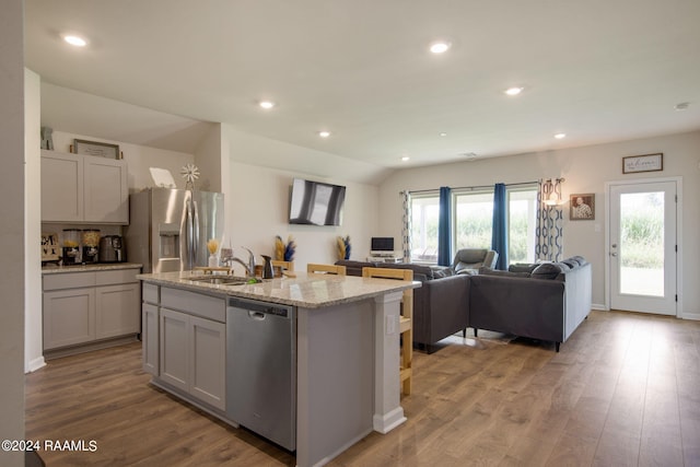 kitchen featuring an island with sink, stainless steel appliances, wood-type flooring, and a healthy amount of sunlight