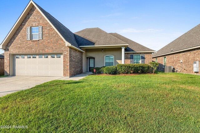 view of front of home with cooling unit, a garage, and a front yard