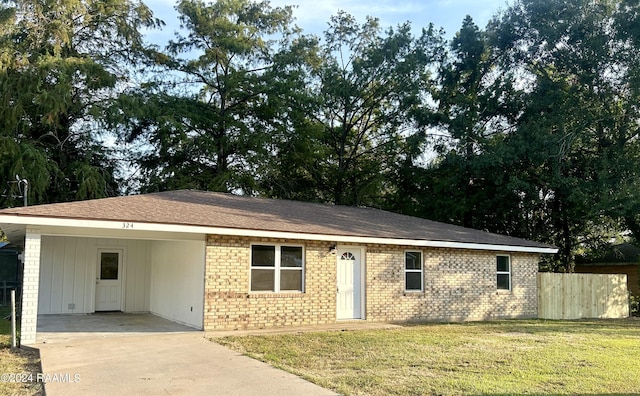 ranch-style home featuring concrete driveway, an attached carport, fence, a front yard, and brick siding