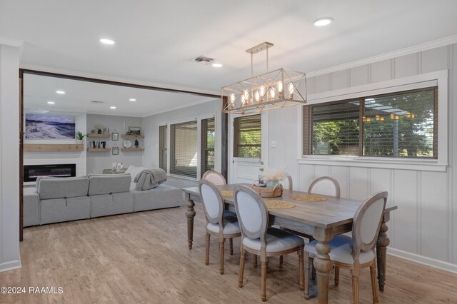 dining space with a notable chandelier, light hardwood / wood-style floors, and crown molding